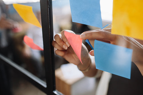 Hands of woman sticking adhesive notes on glass