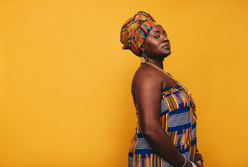 Stylish African woman wearing traditional clothing in a studio