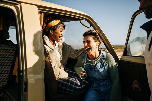 Two friends laugh together on a sunny road trip