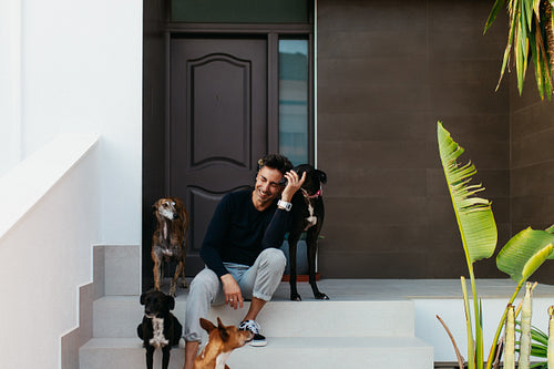 Cheerful pet owner sitting on the porch with his dogs