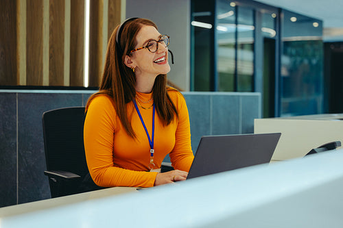 Friendly receptionist in a high-rise office building greeting clients at the front desk