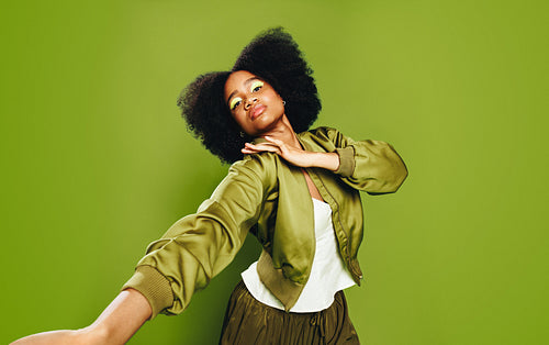 Woman expressing lifestyle identity with confident movement in vibrant green studio portrait