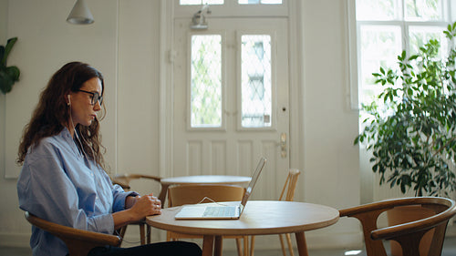 Woman speaks on a video call with laptop in a bright remote work setting