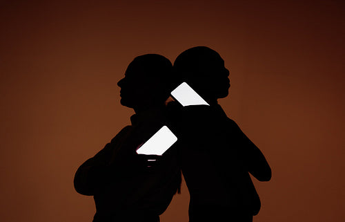 Two silhouetted people with glowing smartphone screens for communication mockups