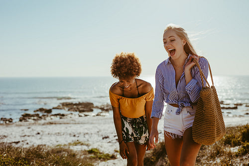 Two happy women walking along the beach