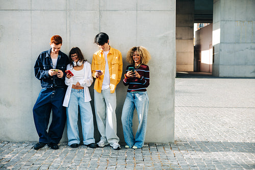 Group of friends using smartphones together outdoors