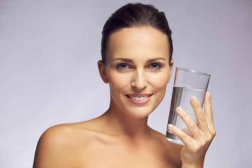 Beautiful smiling woman holding a glass of pure water