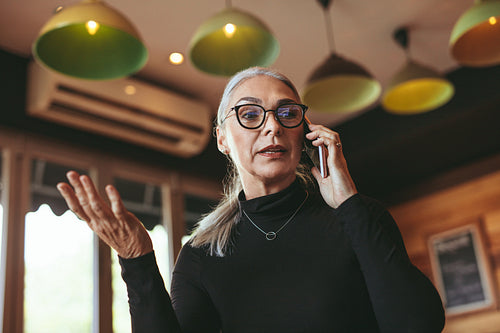 Mature woman talking on mobile phone at cafe