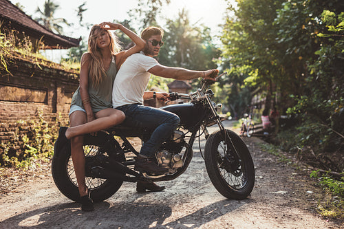 Couple hanging out in countryside with motorcycle