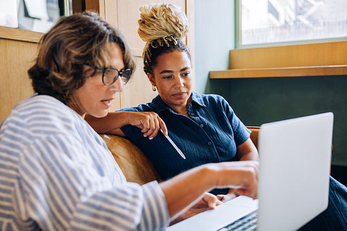 Two women discussing work together while looking at a laptop screen
