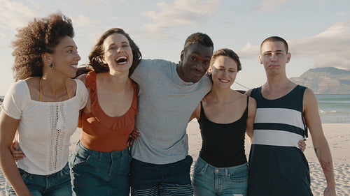 Friends standing together and laughing on the beach