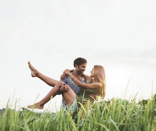 Romantic man carrying woman in field