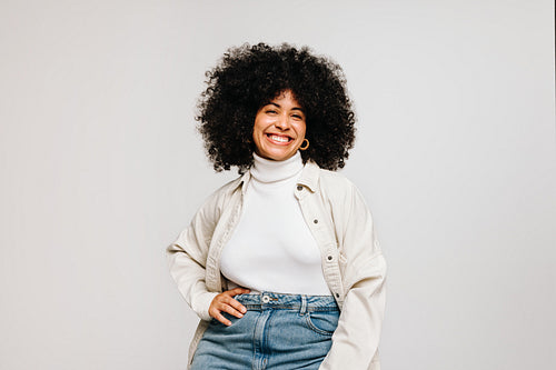 Confident woman with Afro hair smiling at the camera in a studio