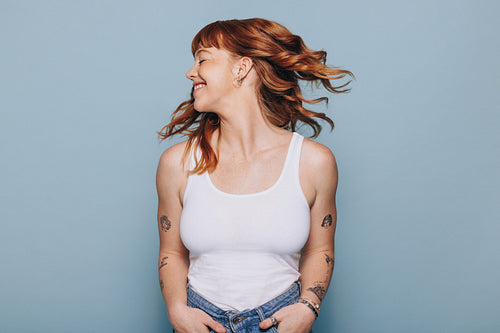 Happy woman flipping her ginger hair in a studio