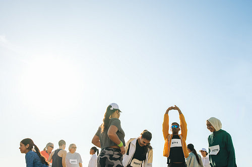 Group of runners stretching before a marathon event on a sunny day