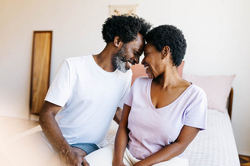 Mature black couple touching foreheads in affectionate moment at home