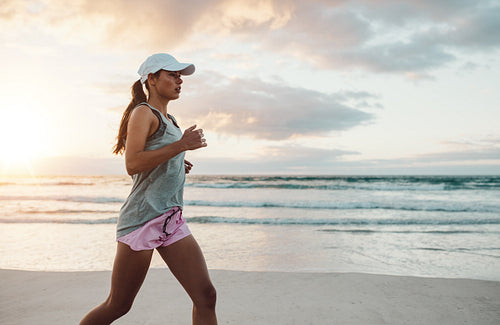 Beautiful young woman jogging on beach