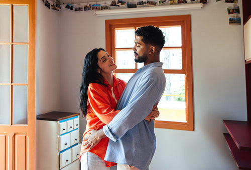 Latino couple embracing lovingly in a modern and cozy home setting