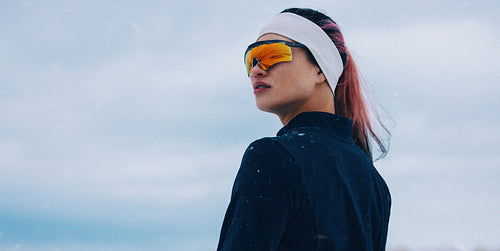 Female athlete poses confidently in winter sportswear with orange sunglasses