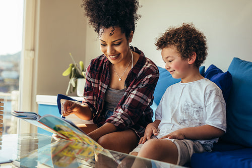 Woman reading a book sitting with her child at home