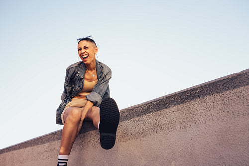 Young woman having fun while sitting on a wall