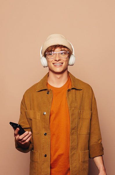 Happy man listening to music on his smartphone with vibrant peach background