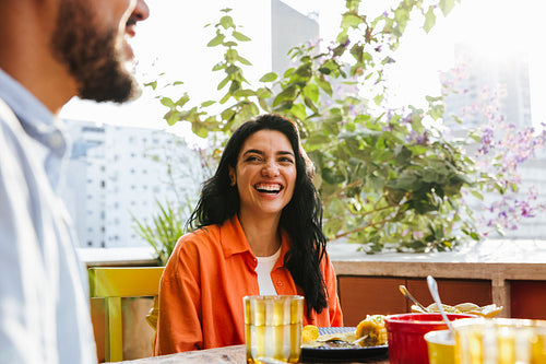 Smiling woman enjoying outdoor meal with friends on a sunny day