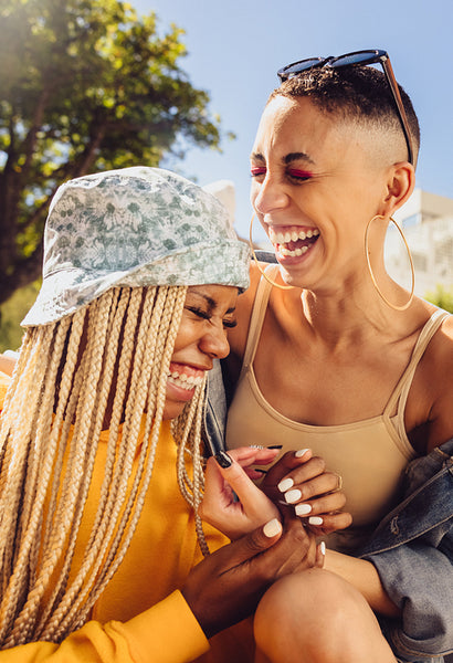 Two female friends laughing together outdoors