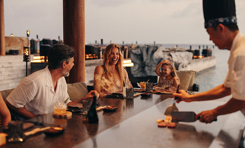 Family enjoying teppanyaki dinner at a seaside gourmet restaurant