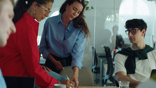 Coworkers follow a business discussion as woman leads the meeting at the conference table