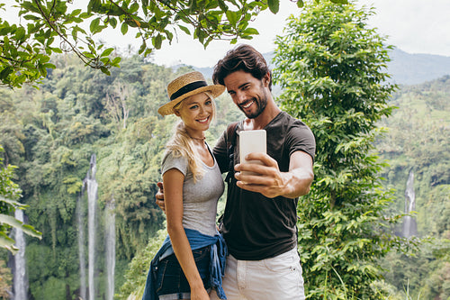 Couple taking selfie with waterfall in background