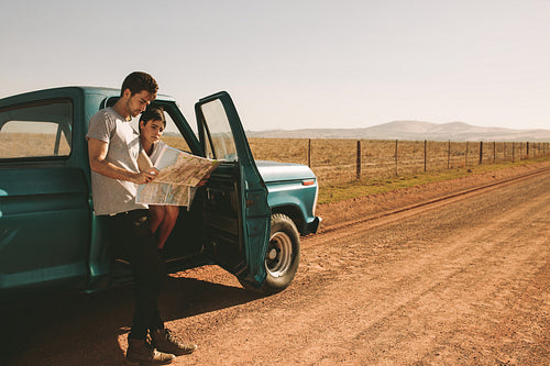 Couple on a road trip looking at map for navigation