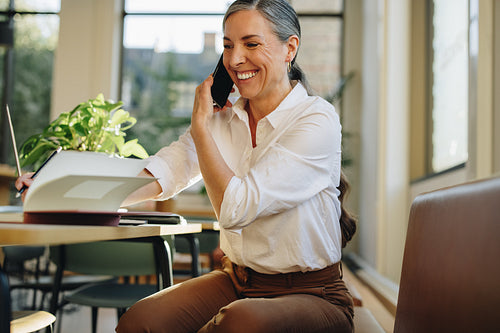 Female professional taking notes while speaking on cell phone