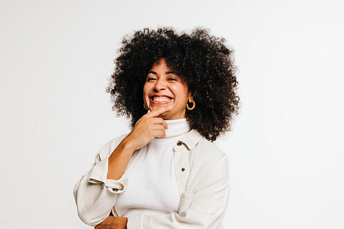 Cheerful woman with curly hair smiling at the camera in a studio