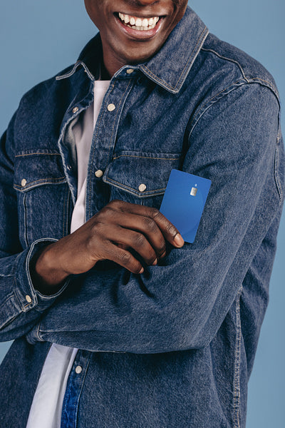 Denim-dressed man gets into the lifestyle of contactless payments as he holds out his credit card