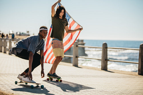 Friends skateboarding on seaside promenade