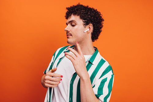 Confident young queer man listening to music in a studio