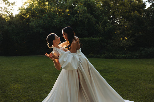 Two brides dancing together in a serene outdoor garden setting