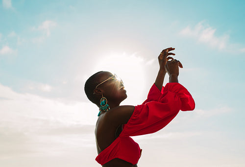 Woman in red dress dancing outdoors on a sunny day