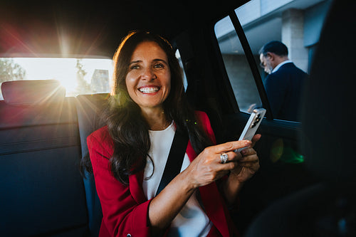 Smiling female executive using smartphone in the car during a sunny day