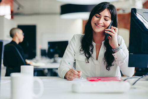 Happy businesswoman making business plans while on a phone call