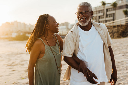 Elderly couple walking on the beach at sunset