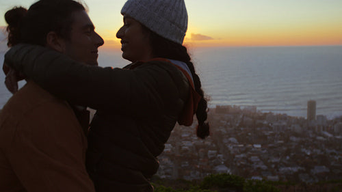 Romantic couple on mountain peak at sunset having fun