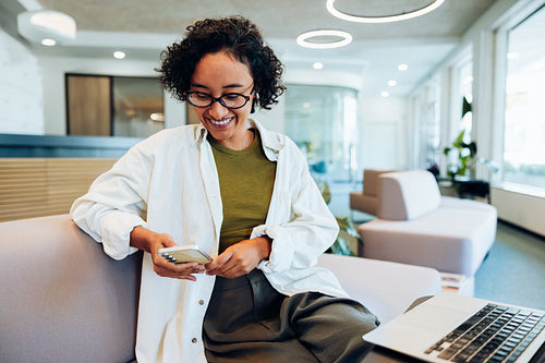 Woman smiles while using phone in lounge