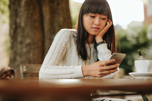 Chinese woman  with mobile phone at outdoor cafe