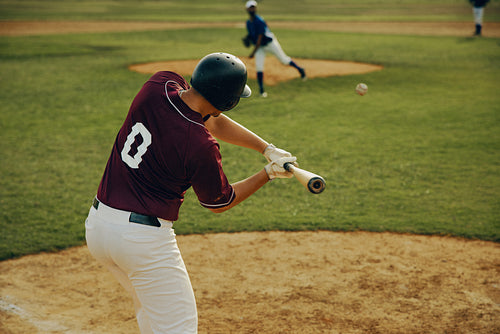 Baseball batter in action mid-swing during a pitch on a sunny day at an outdoor stadium
