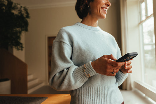 Mobile phone at work: woman using smartphone in bright office
