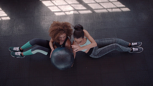 Two women exercising with medicine ball in gym