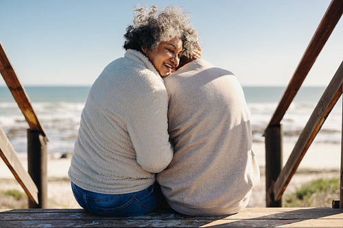 Rearview of a happy senior woman sitting with her husband at the beach