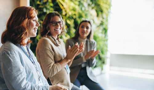 Smiling businesswomen applauding in successful teamwork meeting